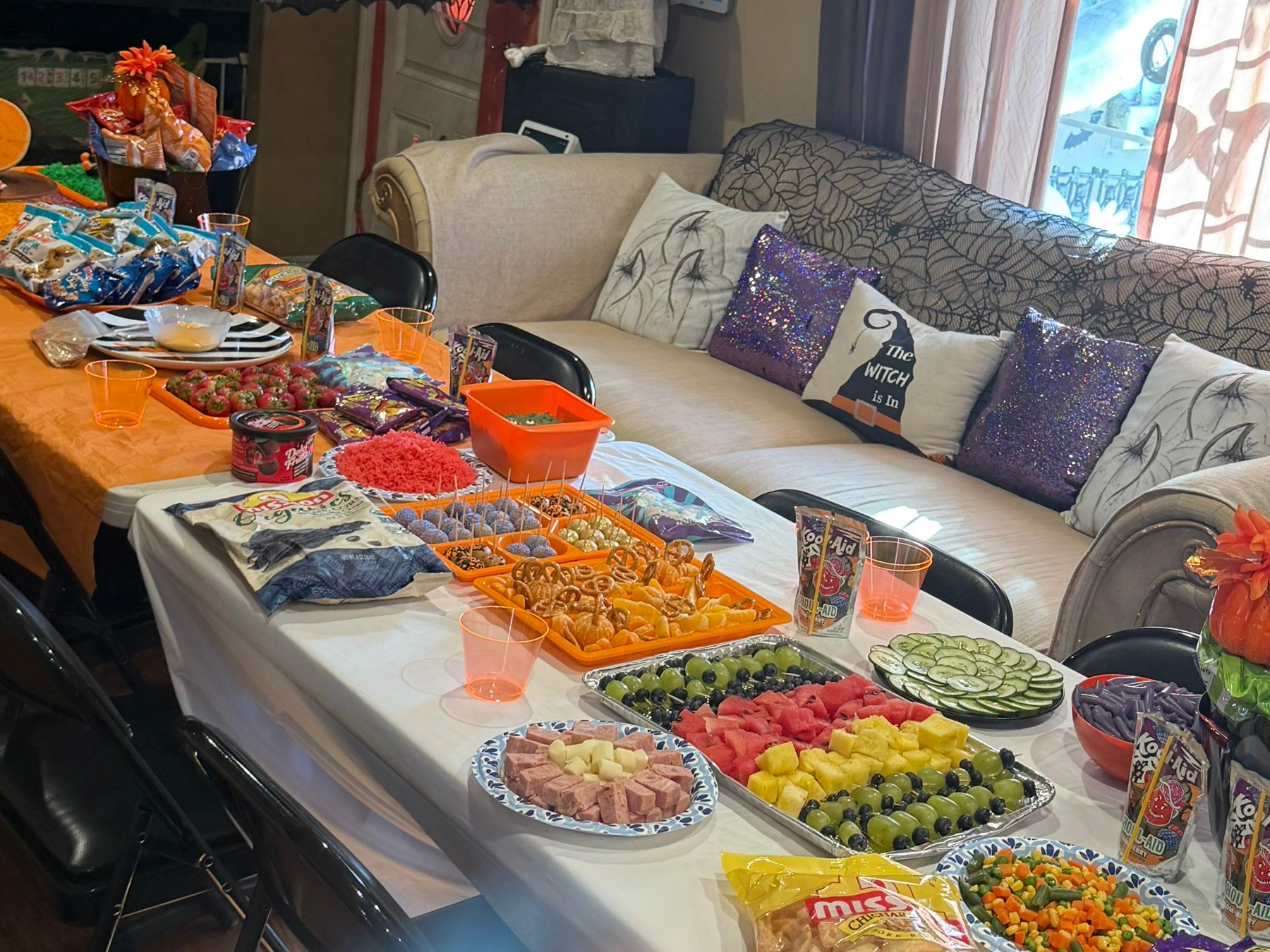 A long table set with fruit and snacks for a Halloween party